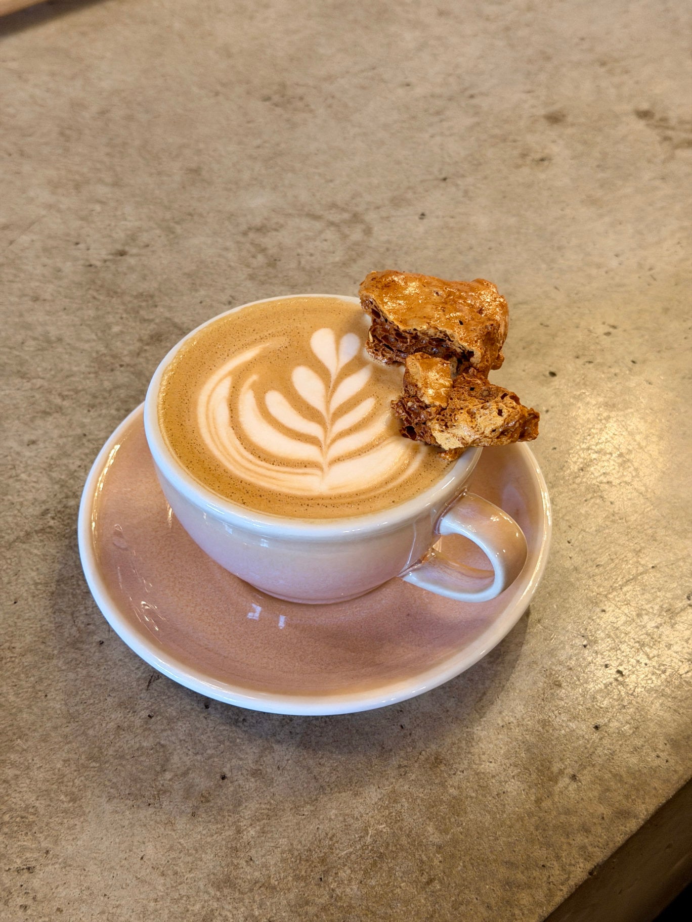 Honeycomb Latte with latte art and house-made honeycomb in a pink cup